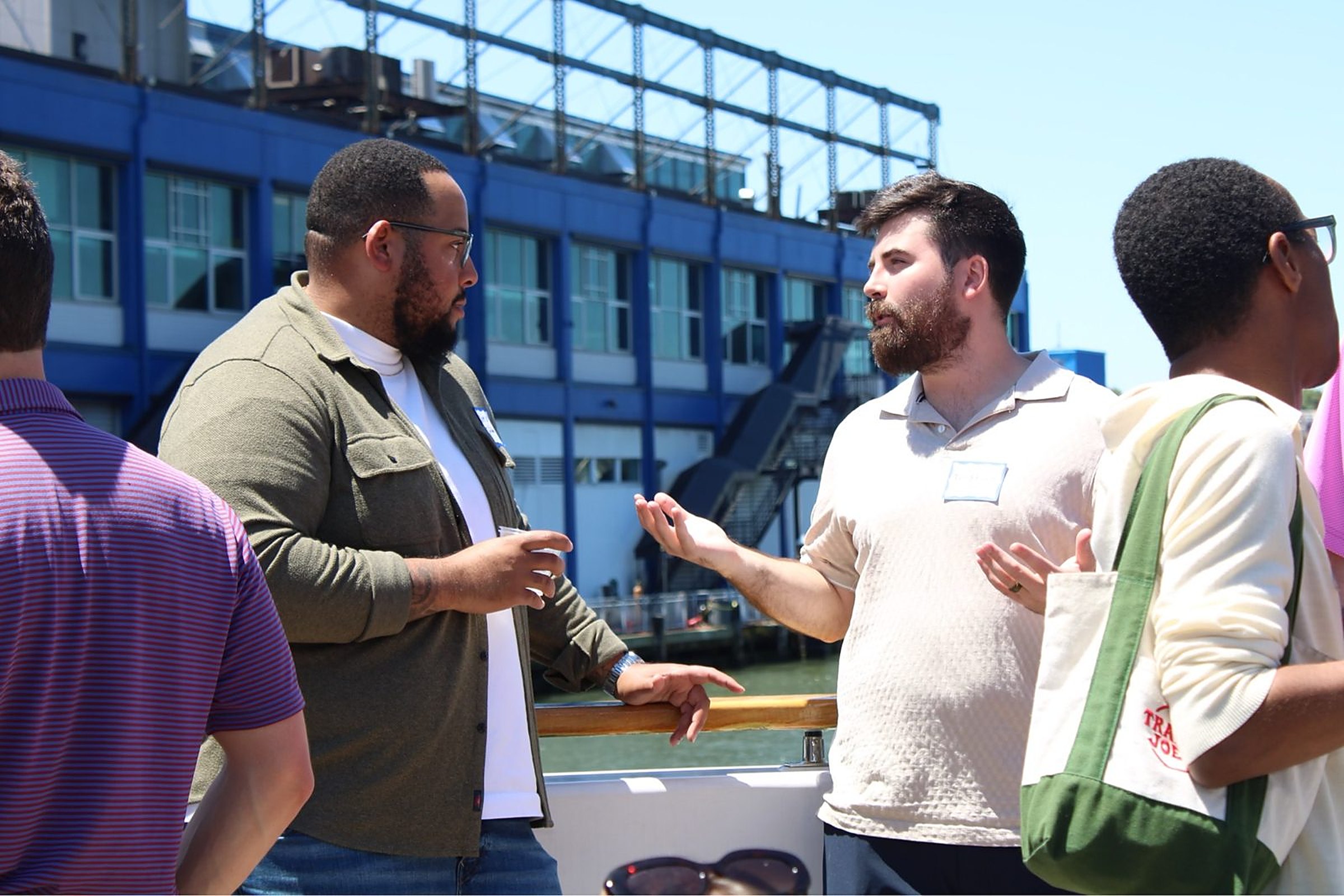 Two attendees in conversation at the rail of the Hornblower Lexington in front of Chelsea Piers at the Heartland Venture Summit
